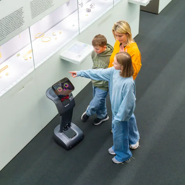 Zwei Kinder und ihre Mutter entdecken mit einem RoboAssistant eine Museumsausstellung